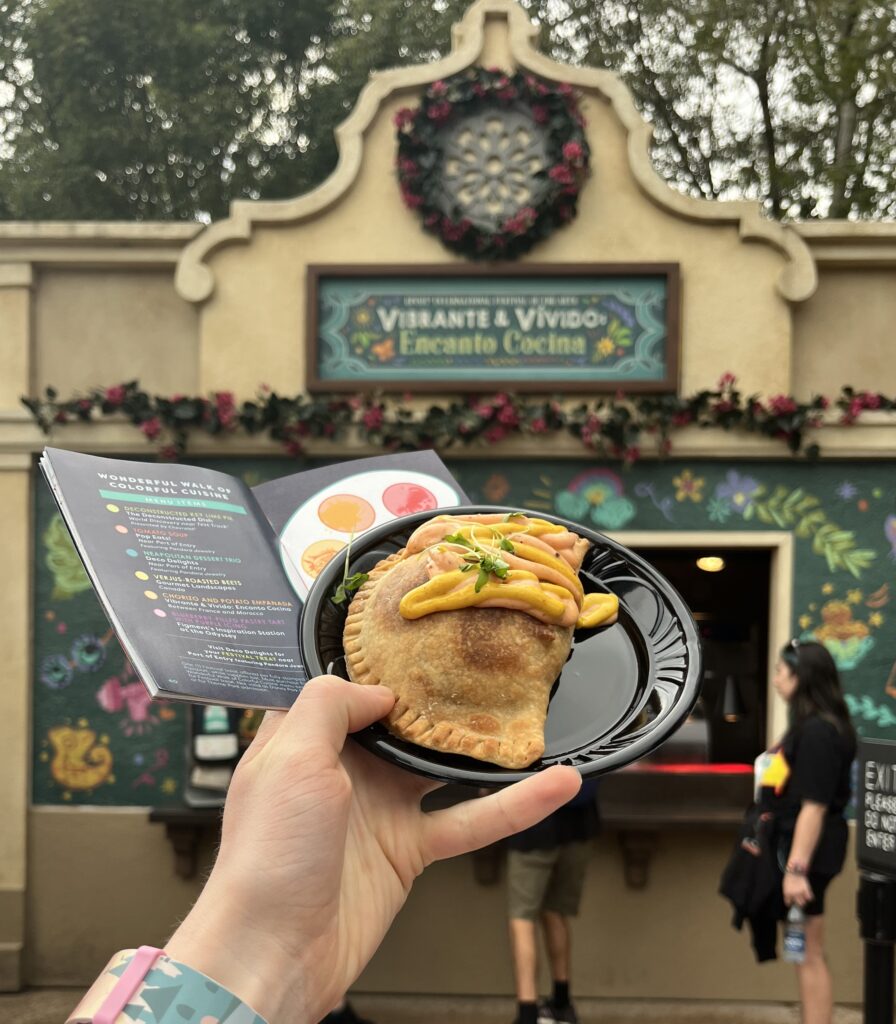 Photo of an empanada and the walk of colorful cuisine stamp page of the festival of the arts guide booklet.