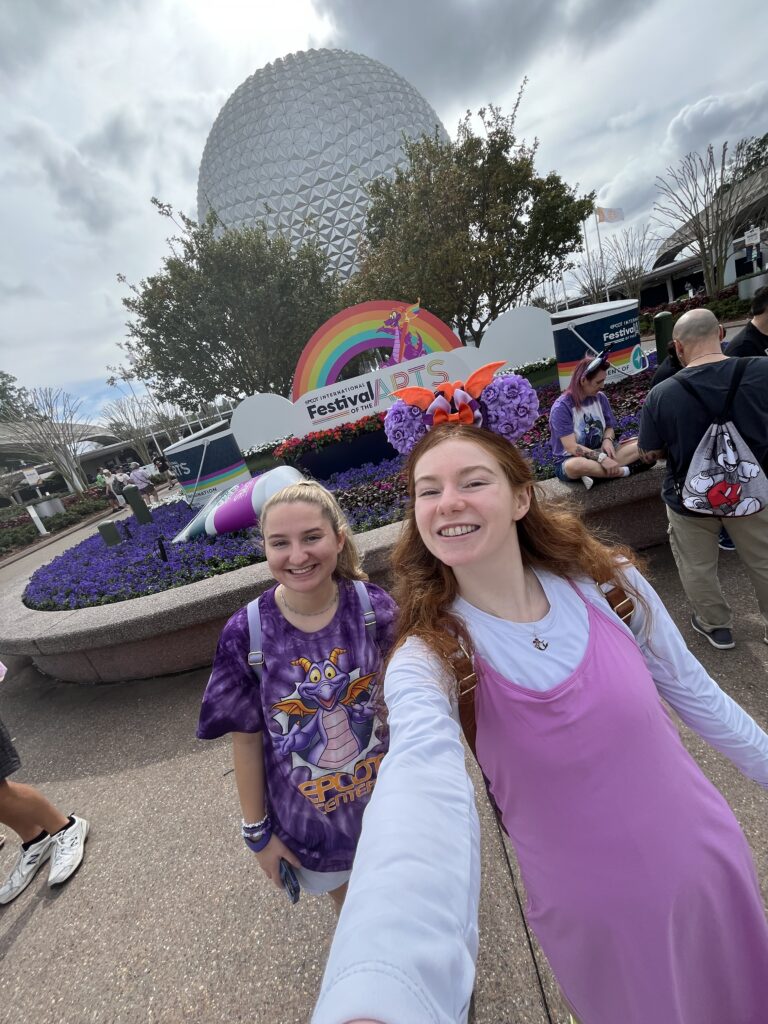 A selfie of Bri and her friend in front of the E.P.C.O.T ball and the FARTS logo.