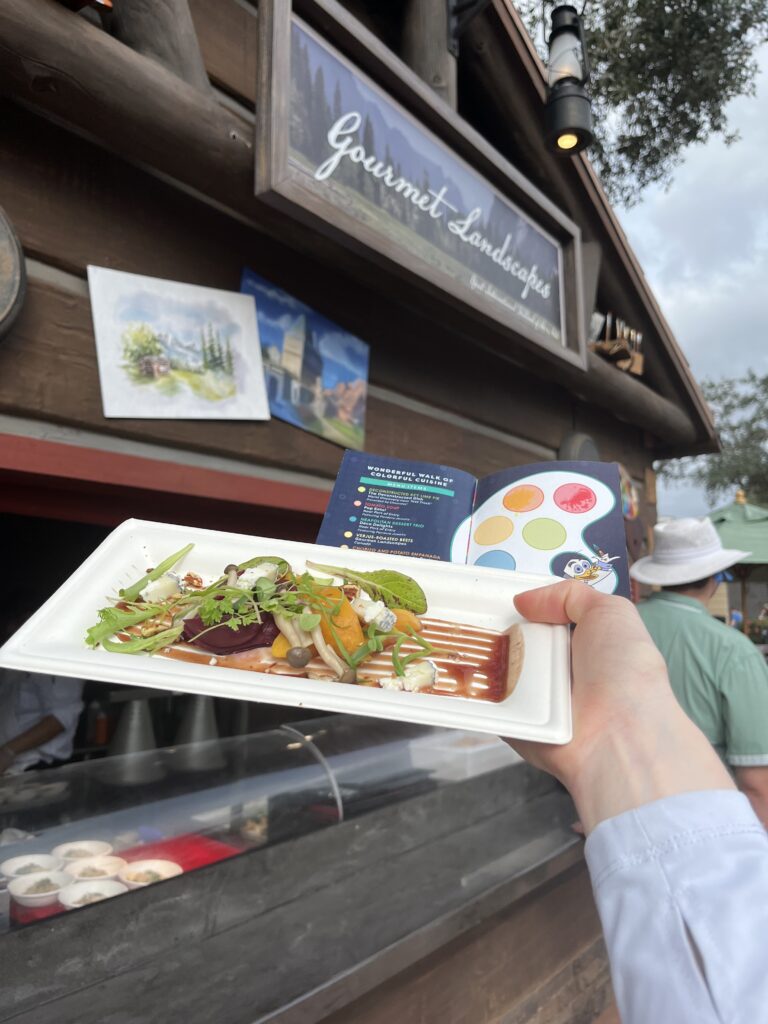 Gourmet Landscapes food booth in background and the rosted beets and goat cheese dish held in the foregrouns.