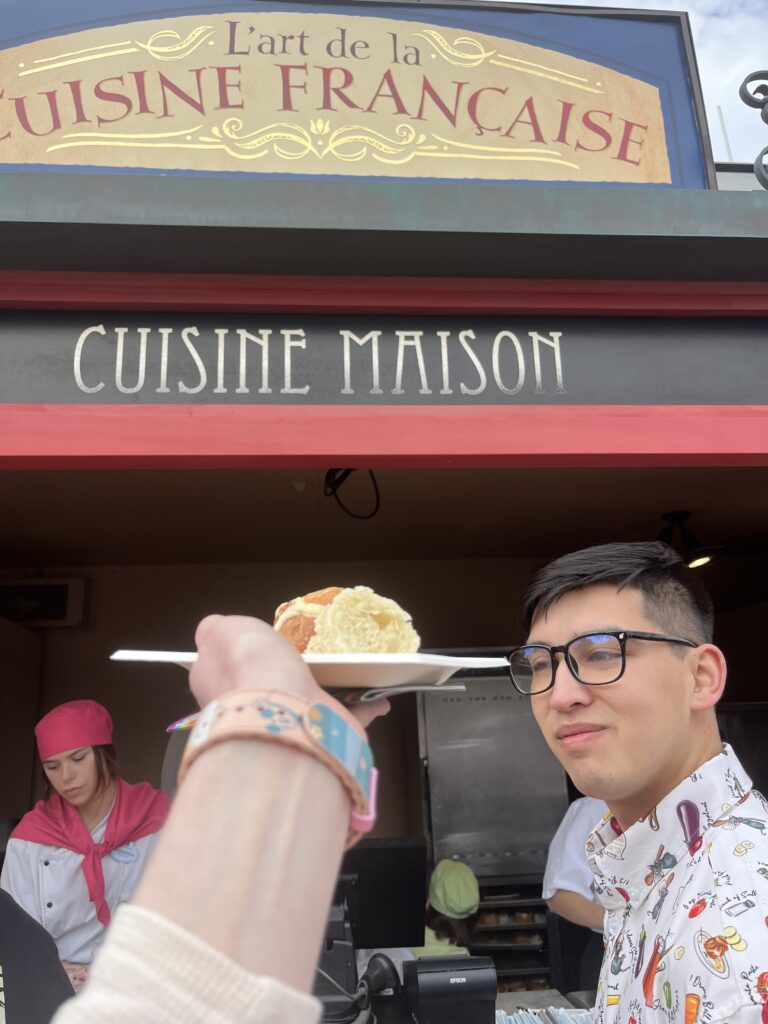 A tiny bread bowl with melted brie held up in front of the Cuisine Francaise food booth.