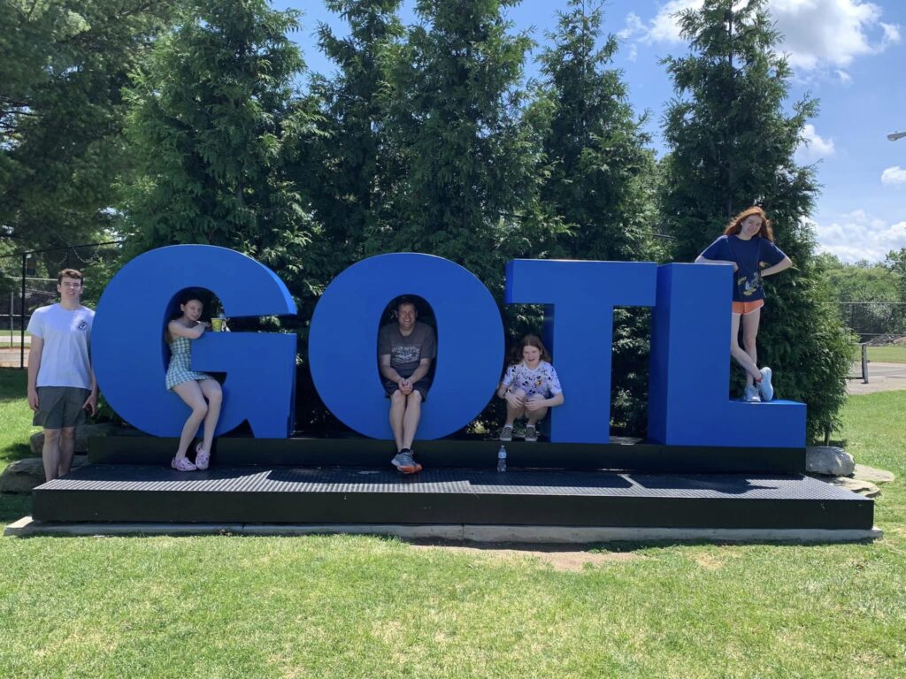 The lyman kids each pose near one letter of the "GOTL" Genova on The Lake sign.