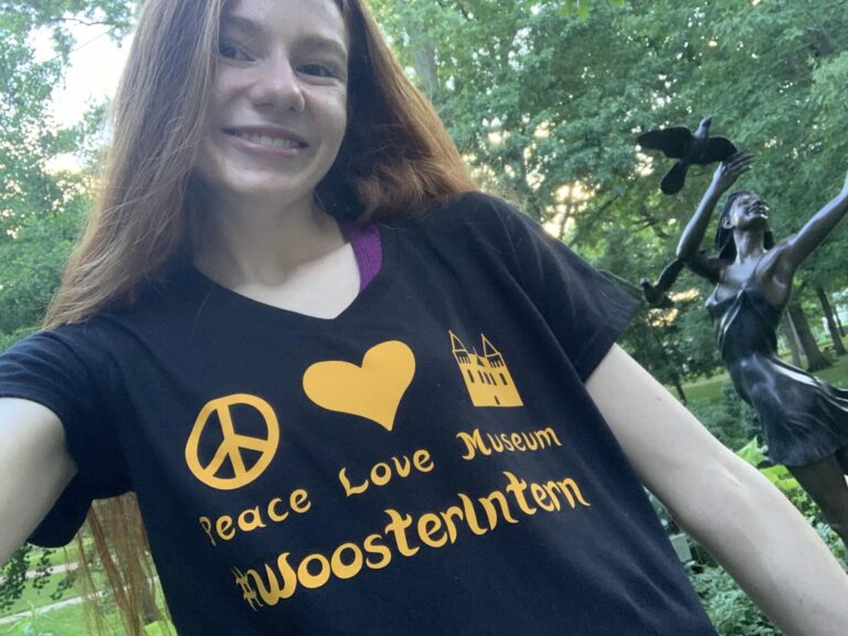 Bri smiles showing off her "Peace Love Museums #Woosterintern" her mom made her