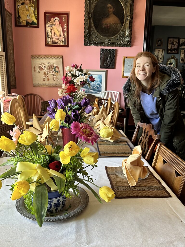 Bri smiles by a table with flowers.
