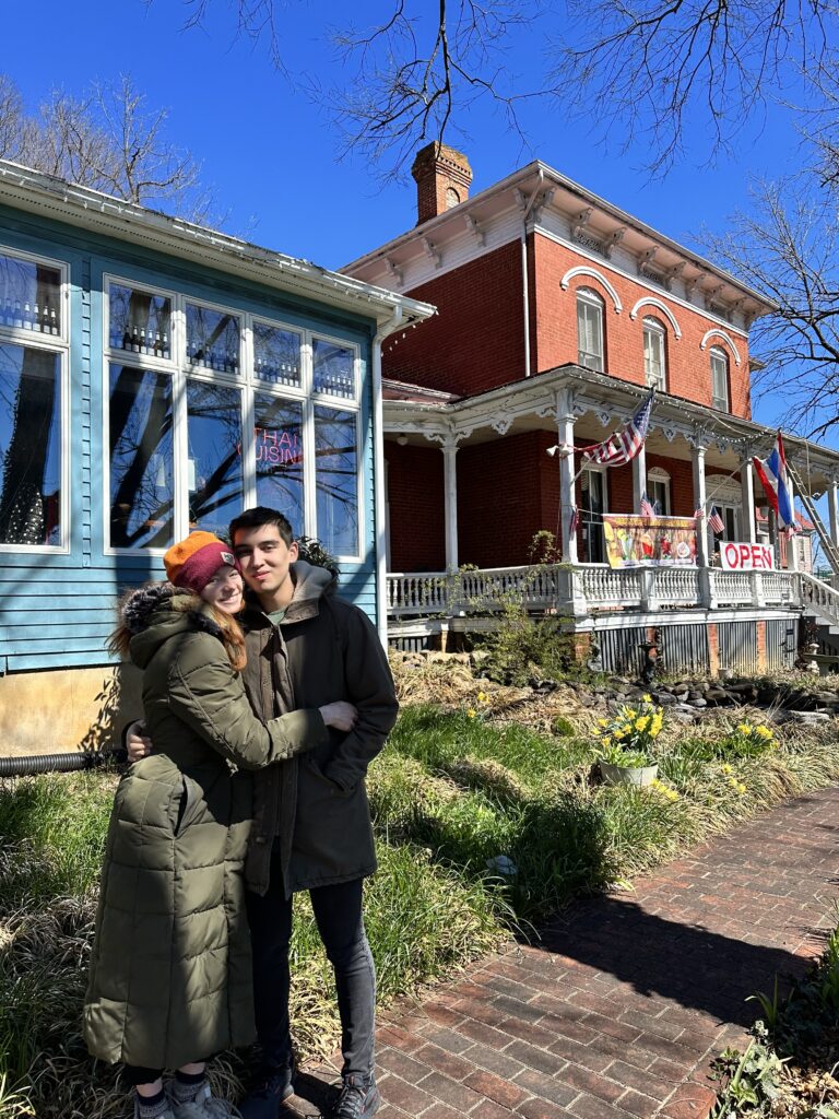 Bri hugs Alix in front of a victorian styled building.
