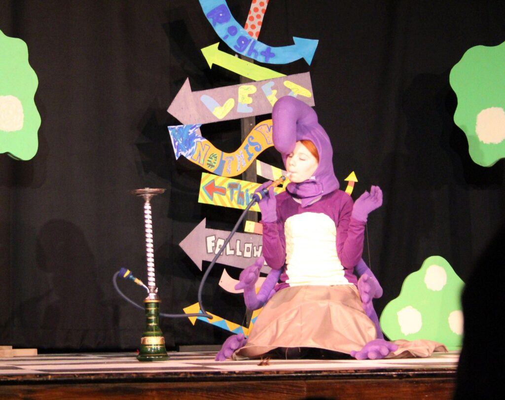 Bri dressed as a caterpillar 'smoking' a pretend hookah as she plays the caterpillar in Alice in Wonderland