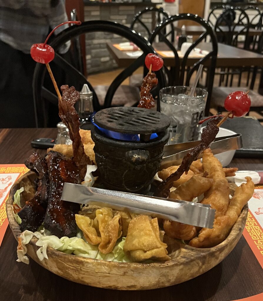 The pu pu platter is served with traditional chinese appetizers and there is a live flame in the center.