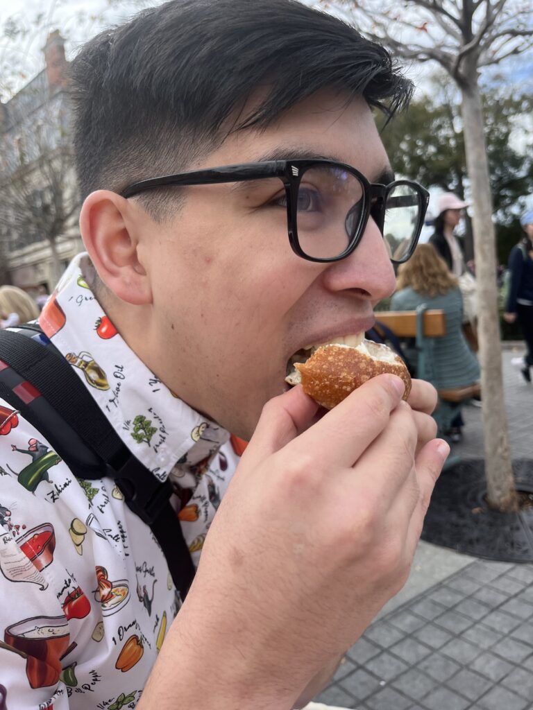 Alix bites into a bread bowl with brie topped on it.