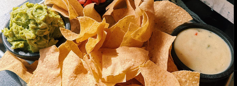 Close up of house-made tortilla chips with guac and queso,