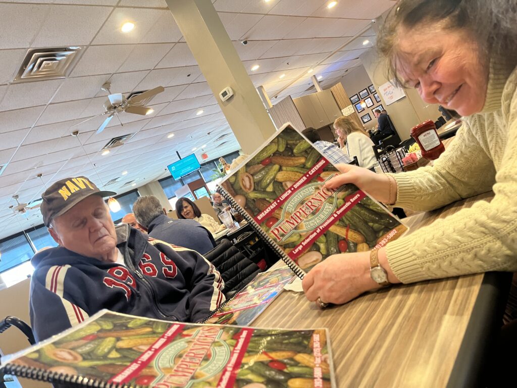 Bri's Nana and Grandpop are shown at a restaurant table with menus in hand.