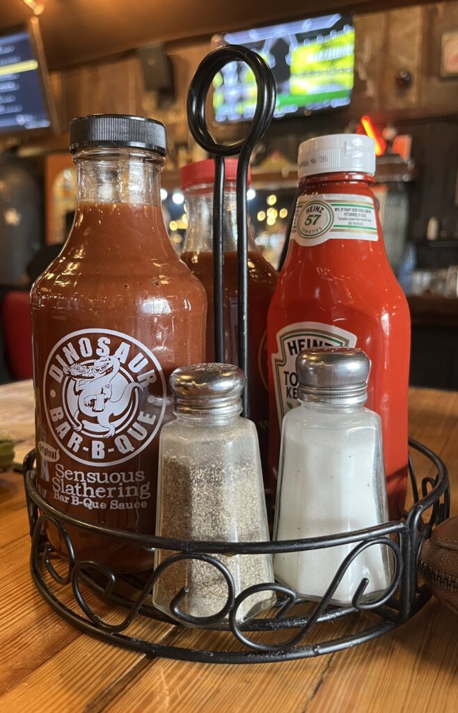 A sauce caddy of ketchup, salt and pepper, sweet BBQ sauce, and spicey BBQ sauce.