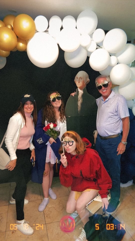 A graduation photo backdrop that Bri poses with Megan and Megan's family.