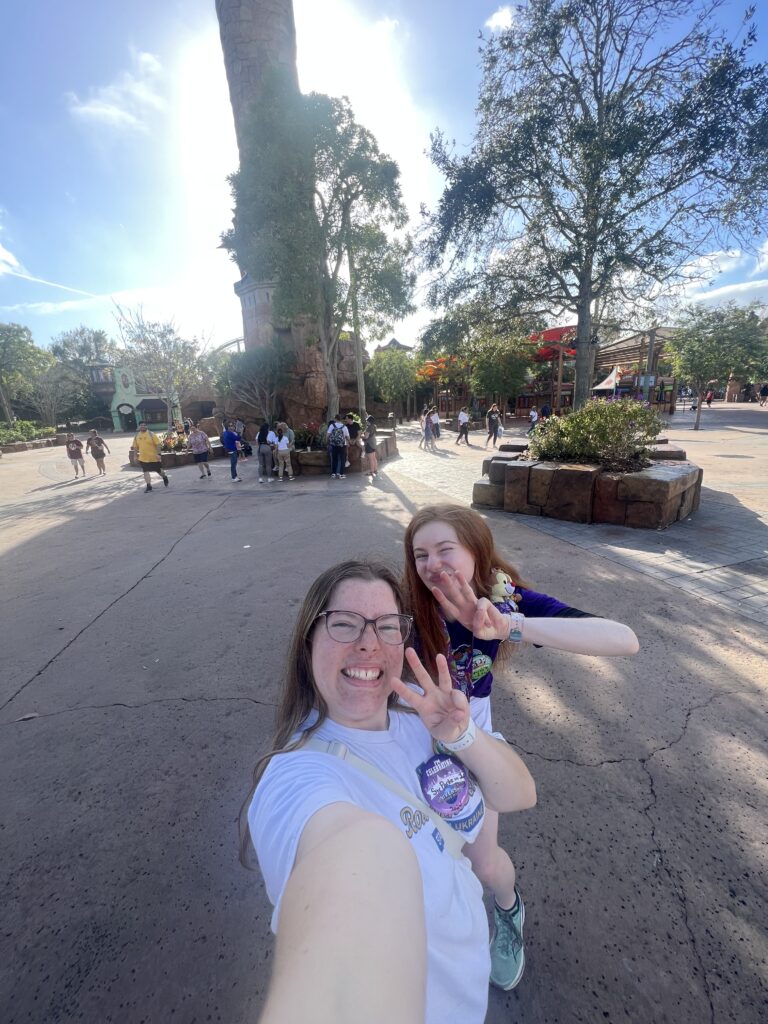 Bri and Sarah hold up three fingers in front of the tower which is Island of Adventure's logo.